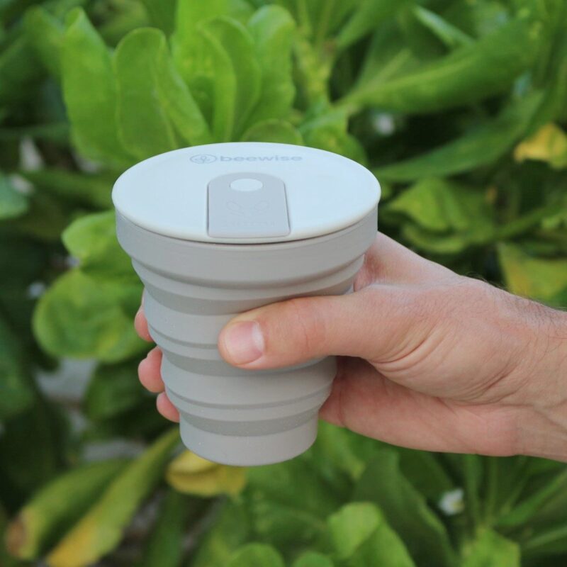 collapsible coffee travel silicone cup hunu with beewise grey warm colour taken by a man hand