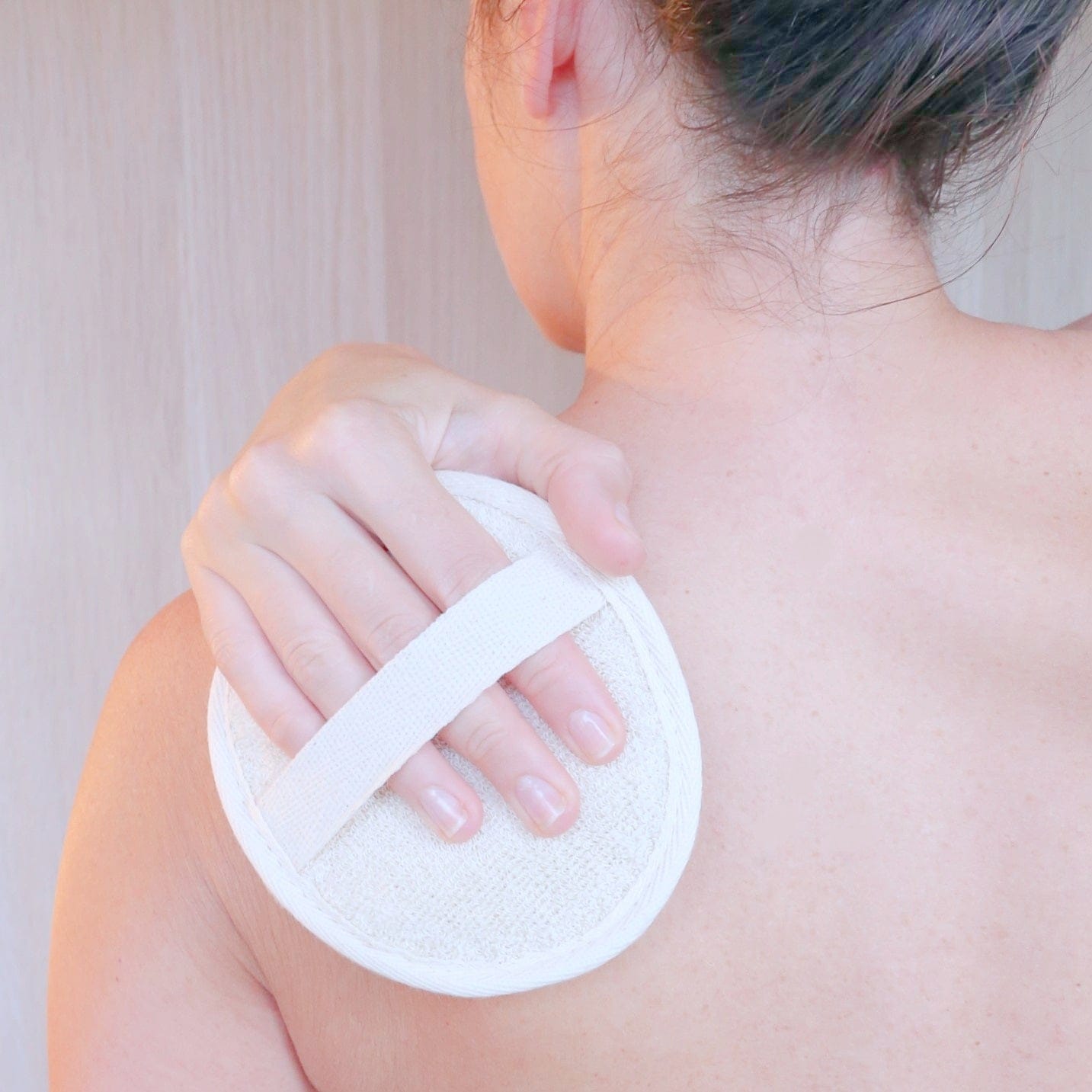 Loofah pad sponge made of natural plant showing being used by a woman to wash her back